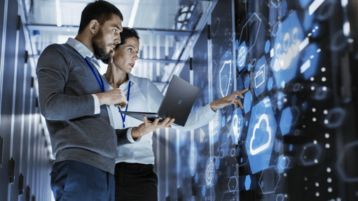 two people infront of a screen looking at data